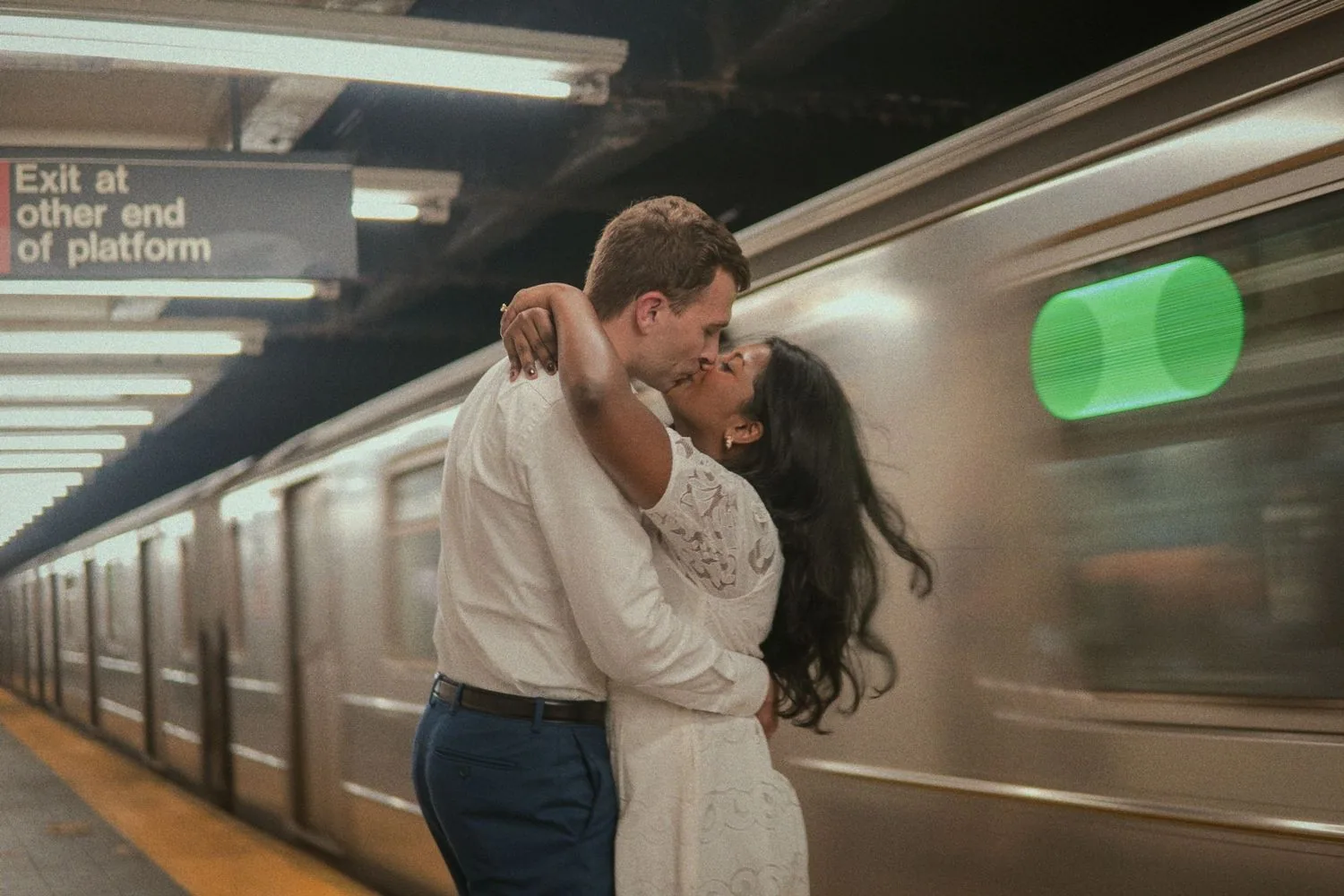 Couple kissing as a New York City subway train passes